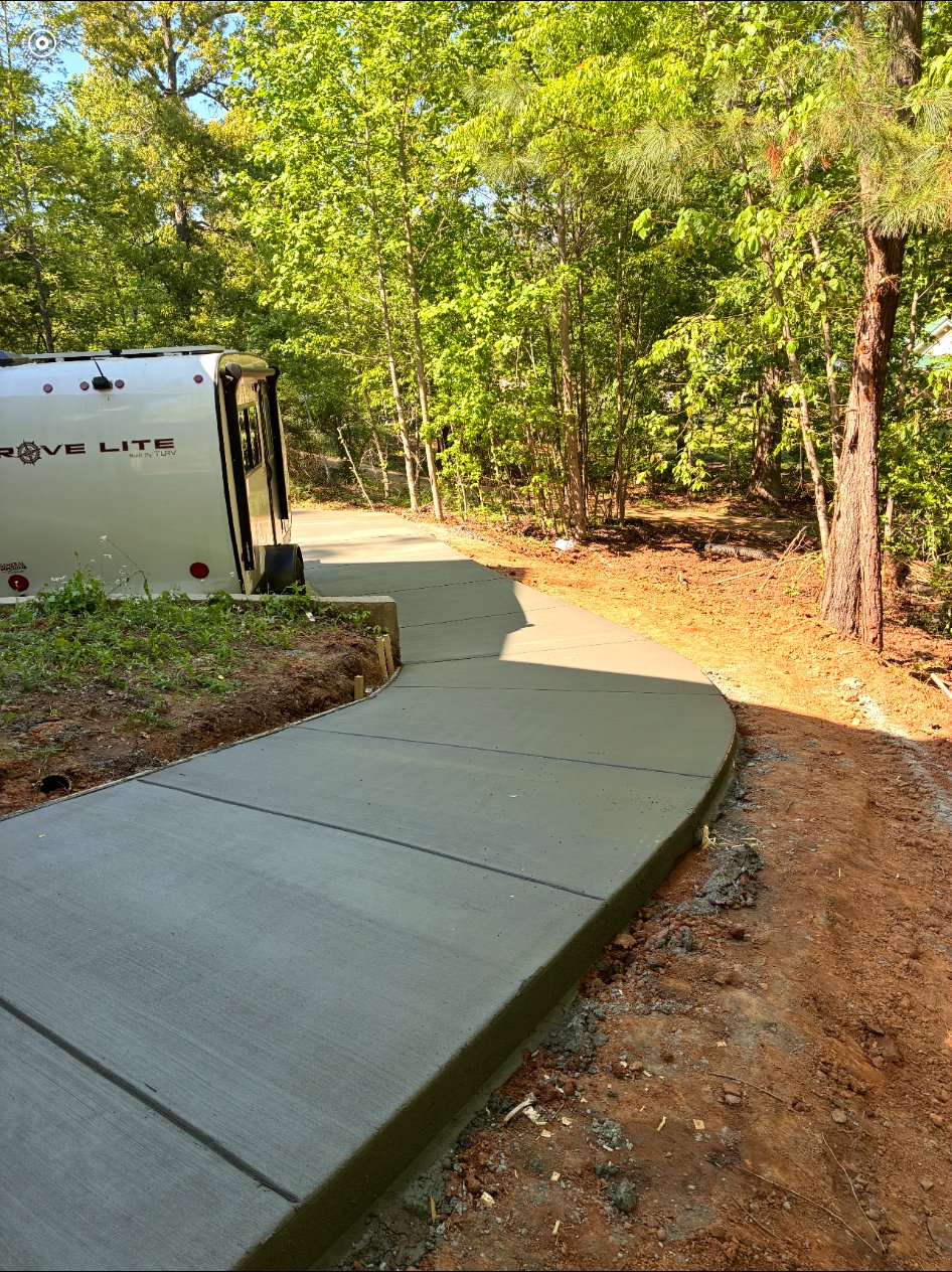Curved concrete walkway leading through a wooded property.